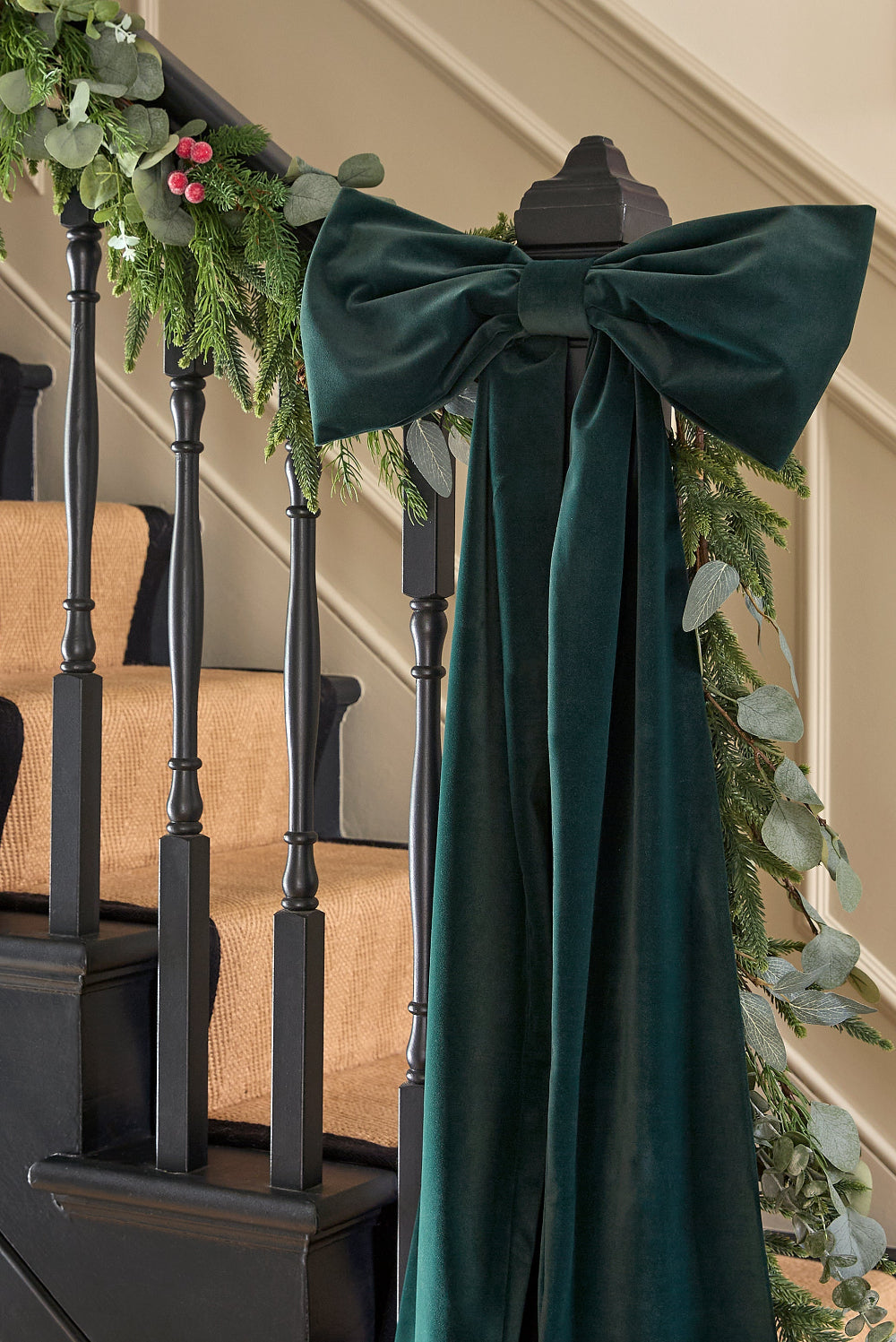Forest green velvet Christmas bow decorating an indoor staircase bannister
