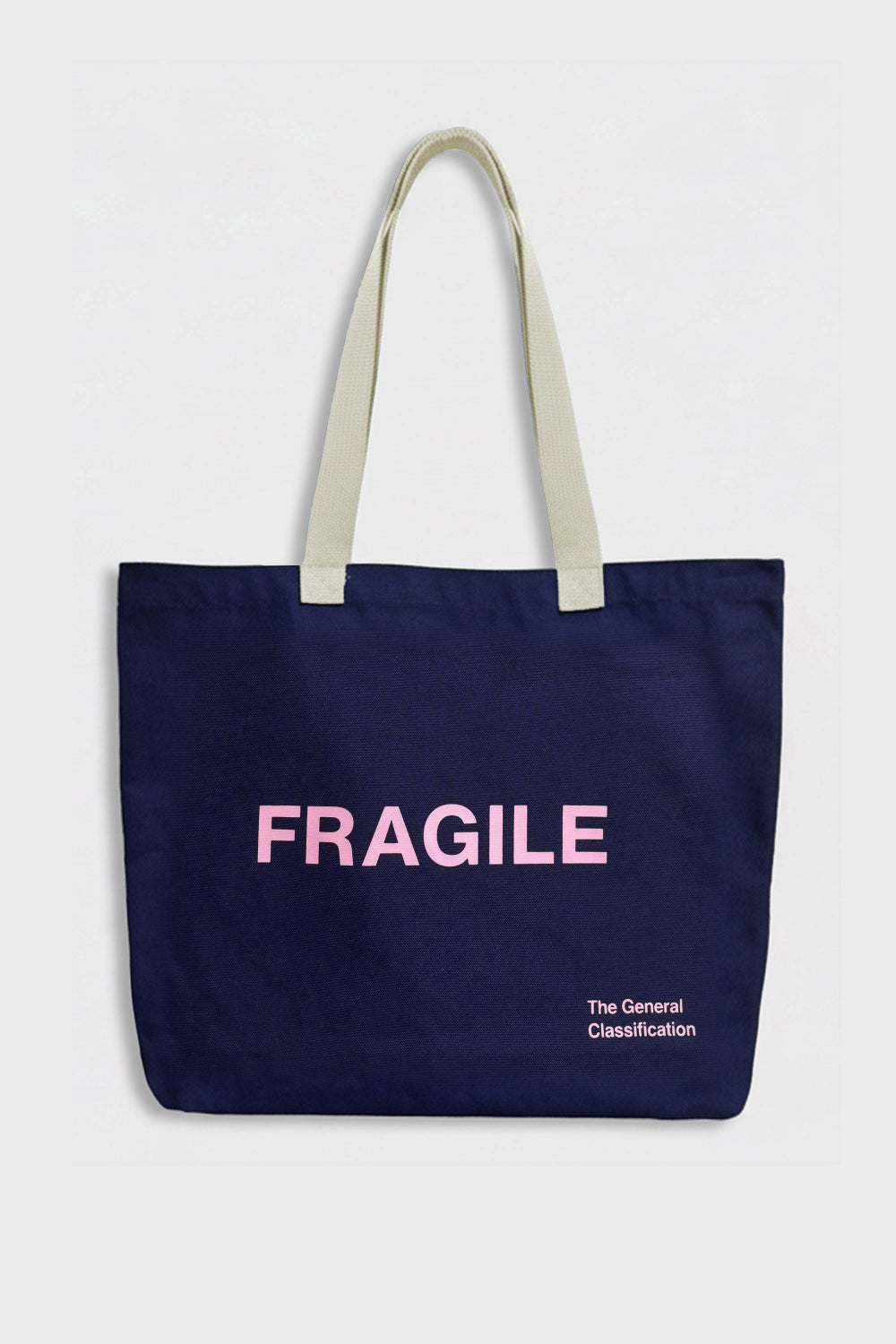 A navy blue canvas tote bag with cream-colored shoulder straps, featuring the word 'FRAGILE' printed in pink across the front, with smaller white text below reading 'The General Classification'.