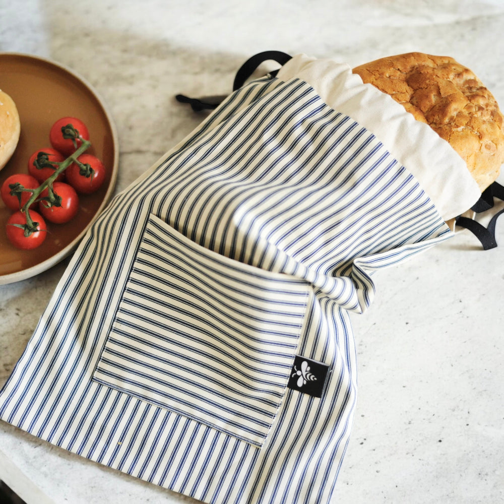 Striped bread bag with a brand logo on a kitchen counter with bread and tomatoes.