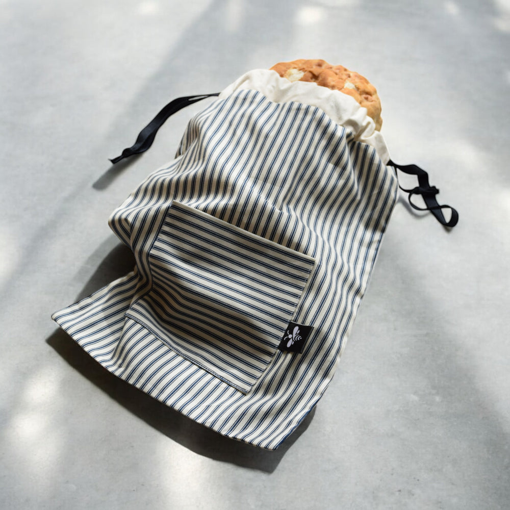 Striped drawstring bag with bread on a grey surface