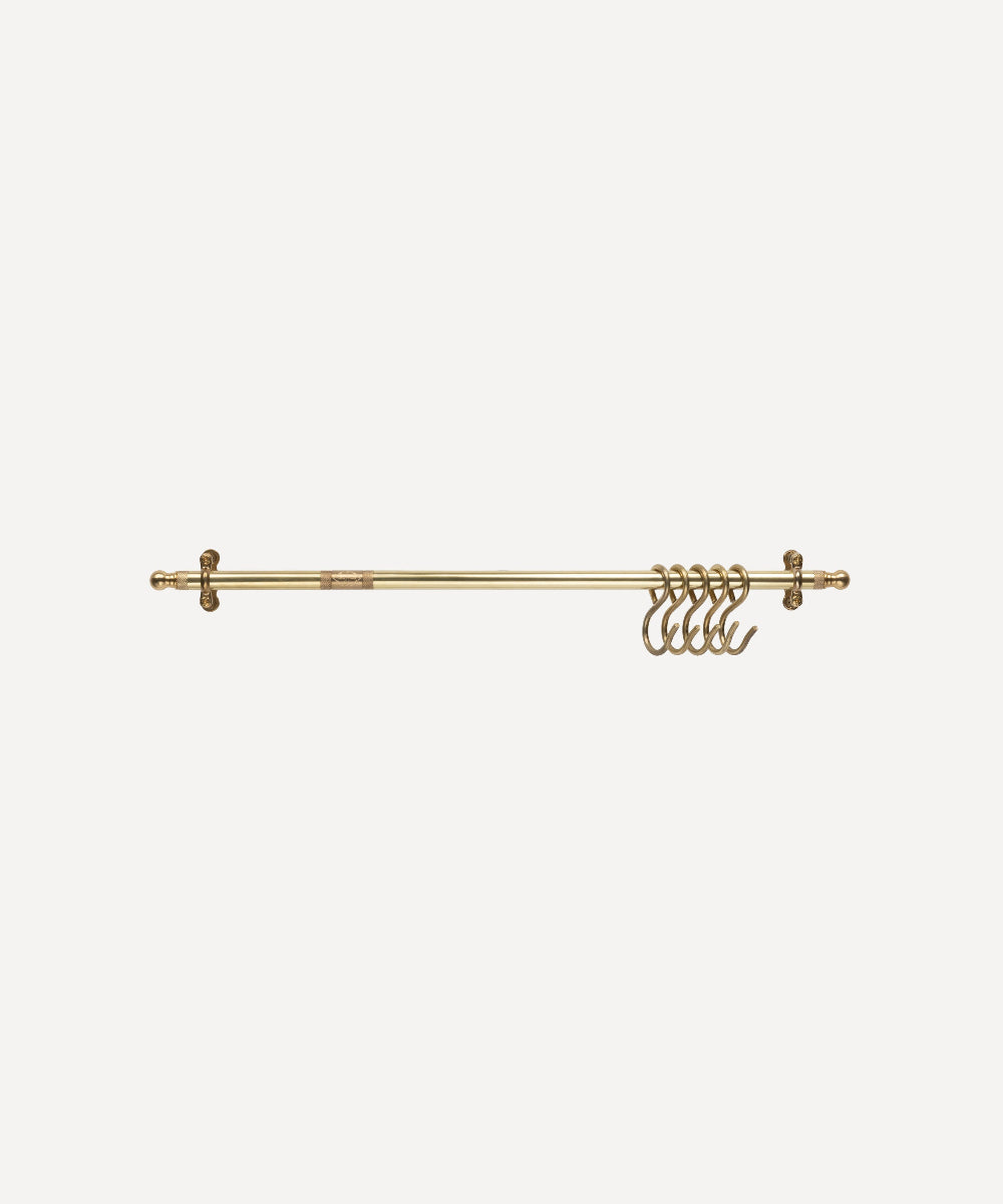 A brass kitchen rail with five hanging rings, shown horizontally against a solid off-white background.
