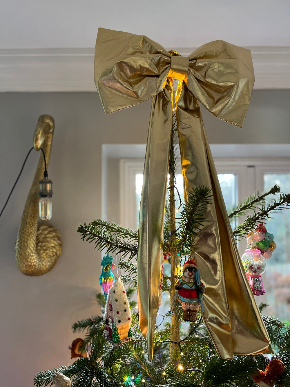 Gold foil Christmas bow styled among decorations on a festive tree