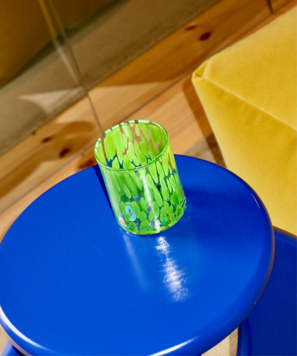 Green Murano Glass tumbler with abstract design on a blue stool indoors
