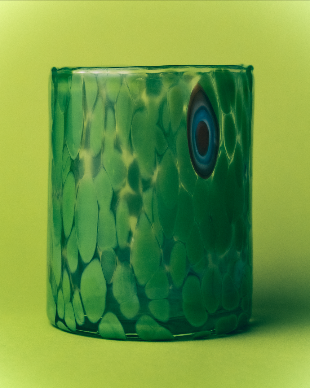 Green glass vase with a blue center on a green background