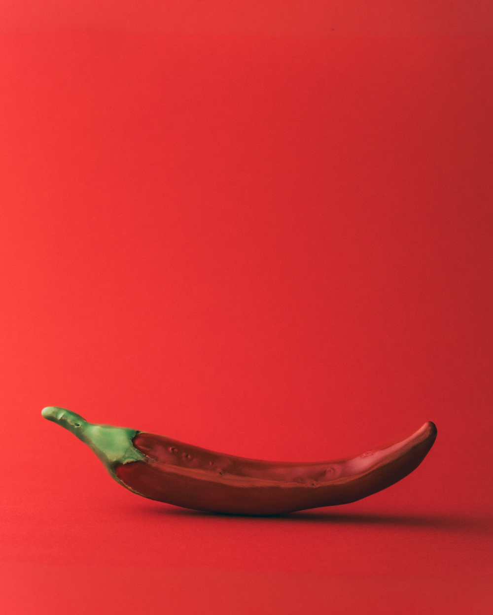 Handmade ceramic glazed chilli on a red background