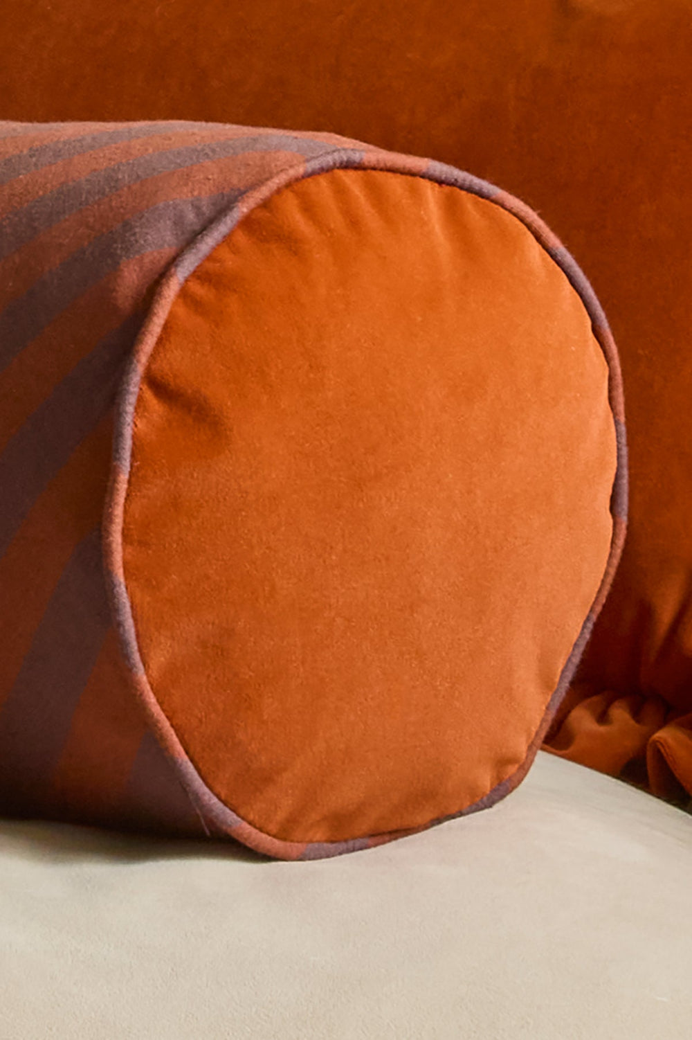 Handmade chocolate and rust bolster cushion with piped edge