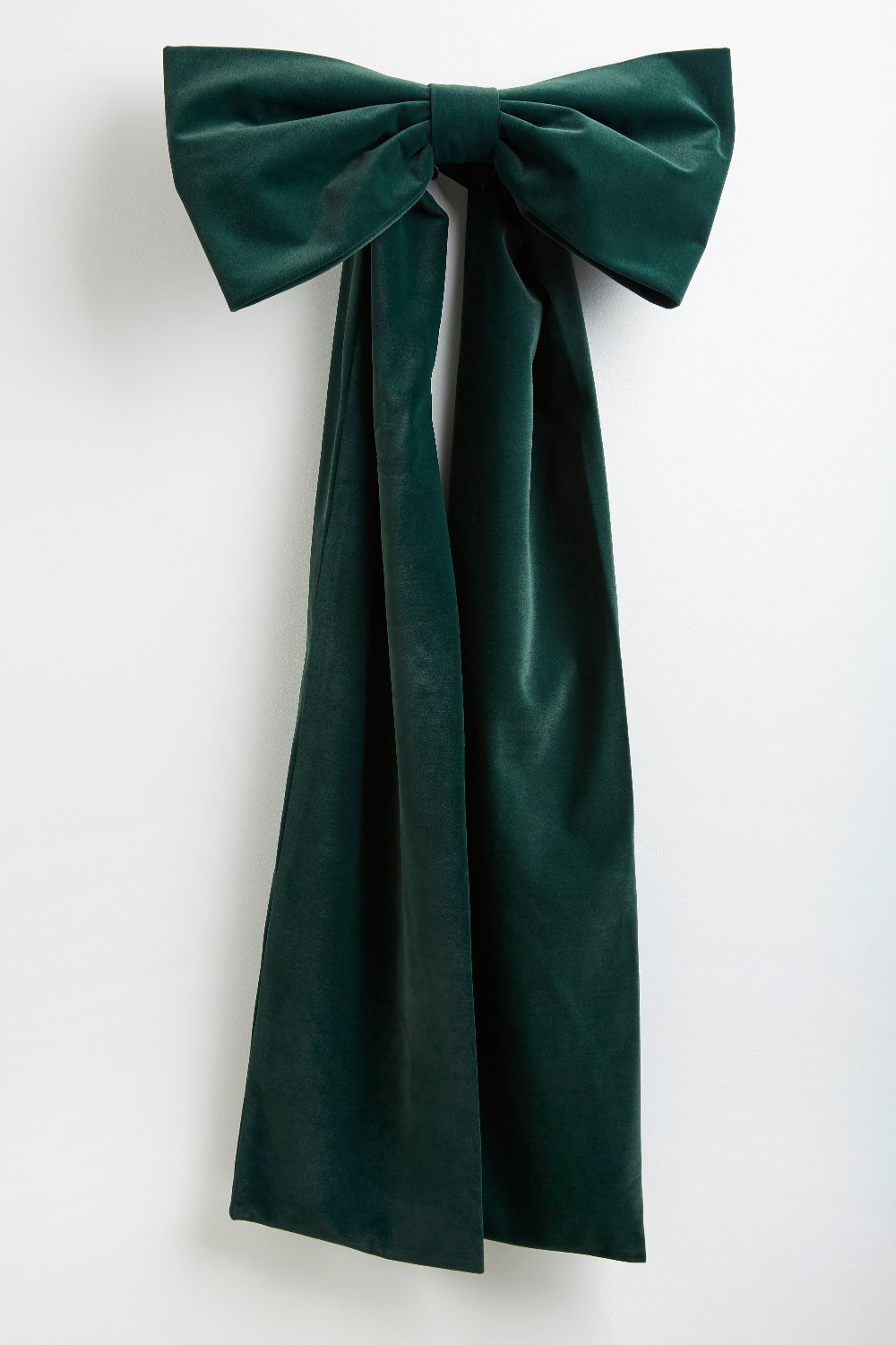 A dark forest green velvet bow with long trailing ribbons, displayed against a clean white background.