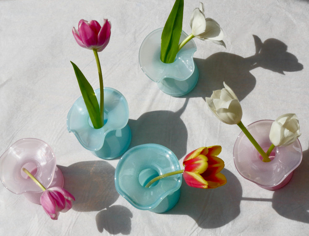 Colorful tulips in transparent vases on a white surface