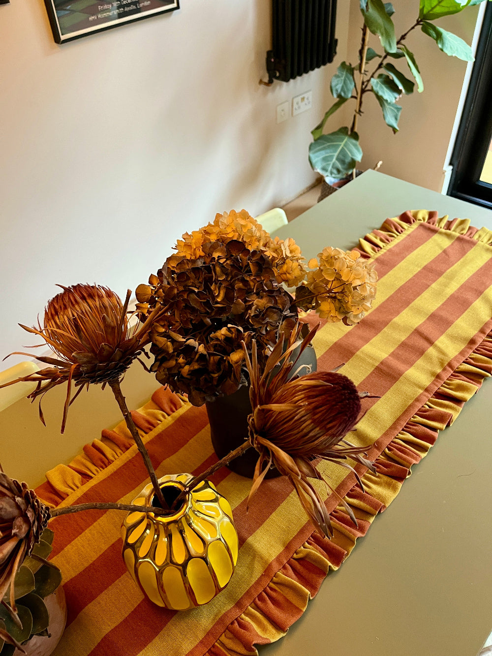 Handmade rust and mustard striped table runner used in a layered table setting
