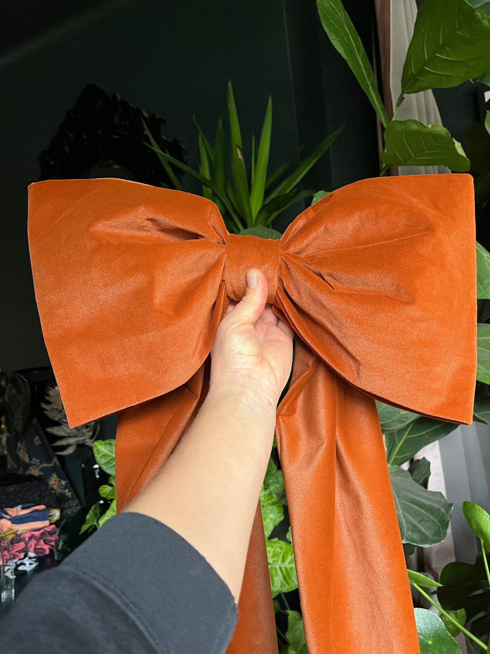 Handmade oversized rust velvet bow being held to show its generous scale
