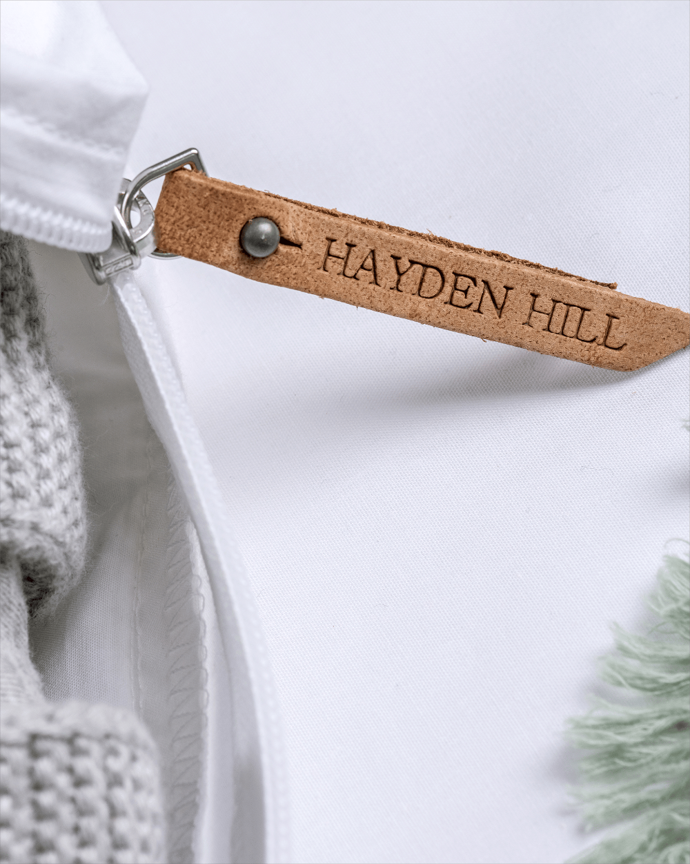 Close-up of a white garment with a brown leather tag labelled 'Hayden Hill'.