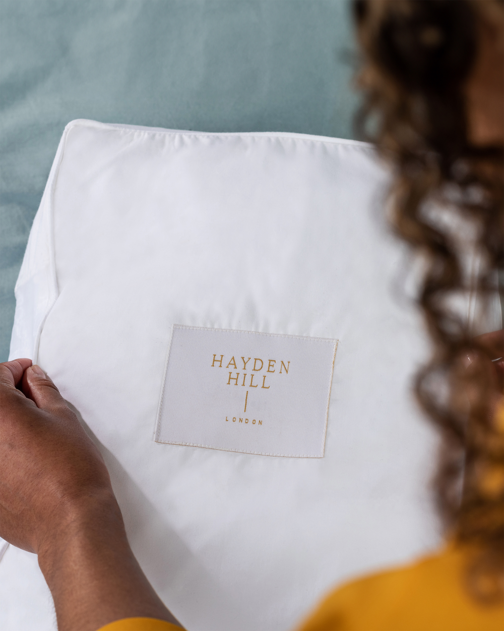 White storage box with 'Hayden Hill London' label held by a person wearing a yellow shirt.