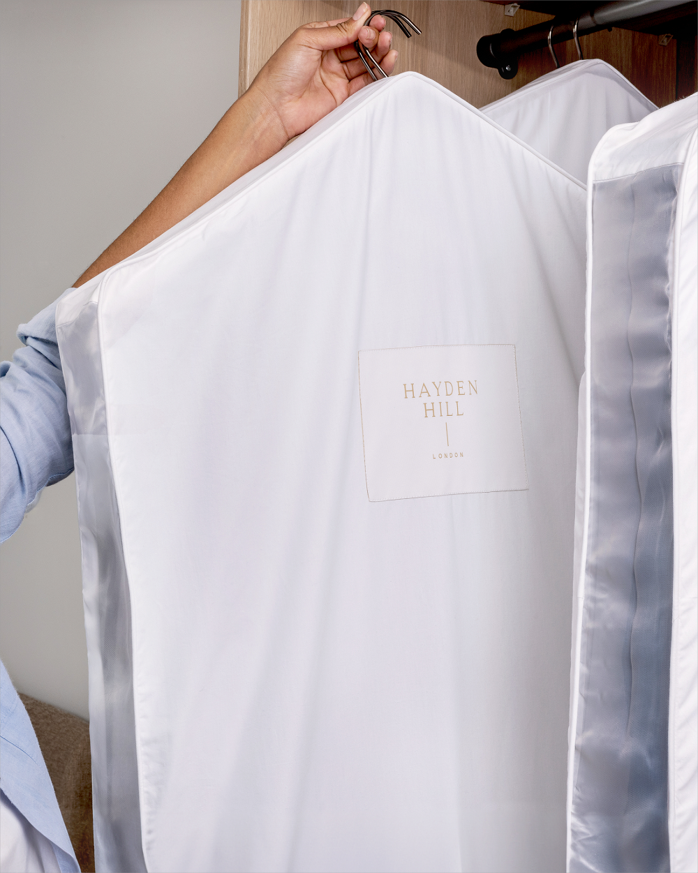 White organic hanging bag with 'Hayden Hill' branding held by a person against a neutral background