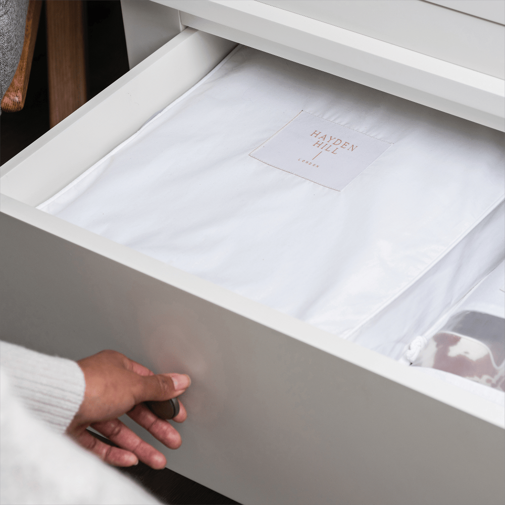 White drawer with folded white sheets and a Hayden Hill label.