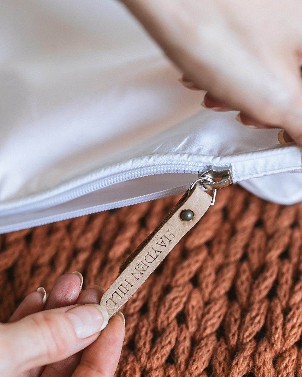Close-up of a white cotton hanging bag with a leather tag on a textured brown surface