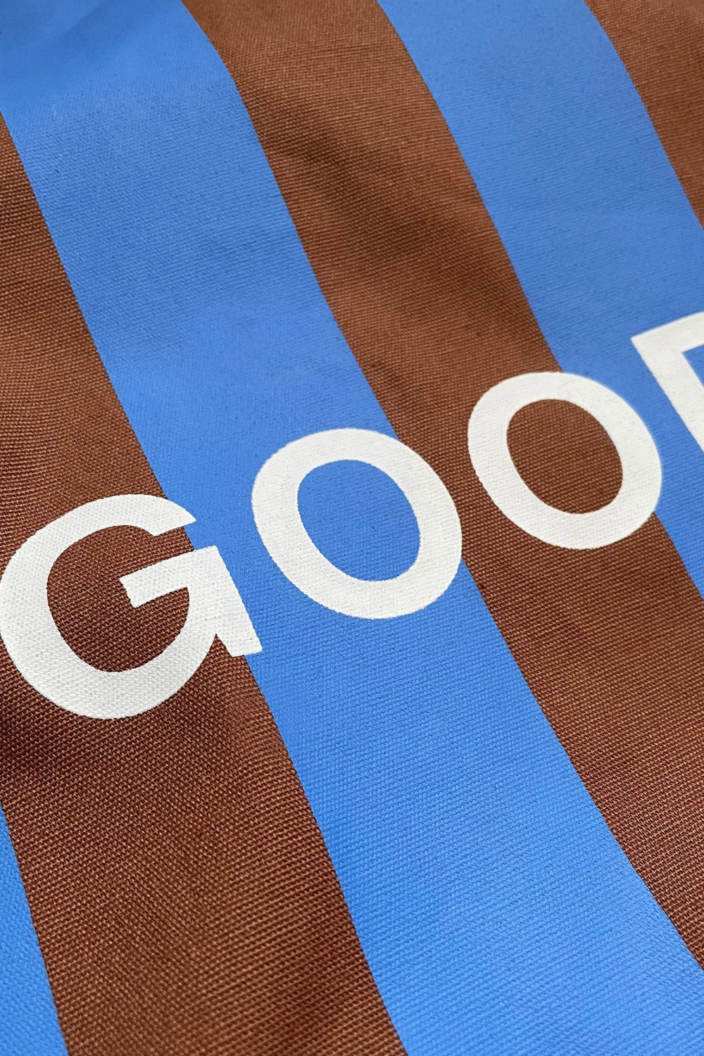 Close-up of a fabric with brown and blue stripes and partially visible white text.