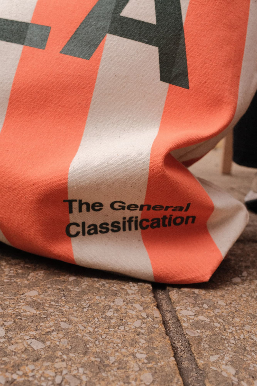 Orange and beige bag with 'The General Classification' text on a concrete surface