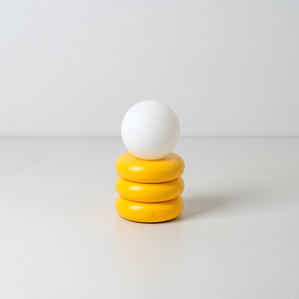 A yolk yellow cordless rechargeable table lamp with a contemporary tubular structure, displayed against a neutral background.