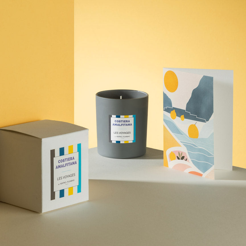 Candle with packaging and a card on a yellow background