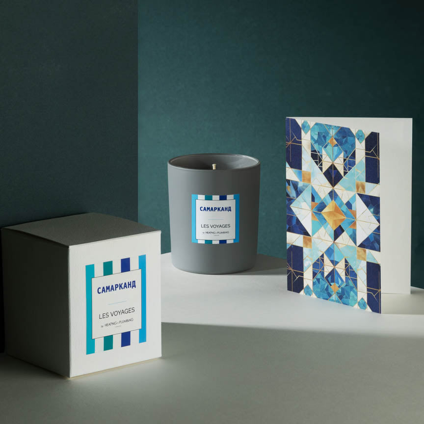 Candle with packaging and decorative card on a dark surface