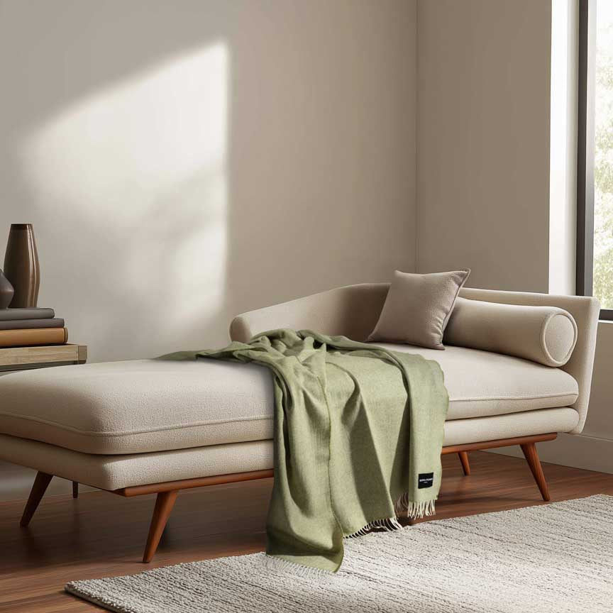 Beige chaise lounge with a green blanket in a modern living room.