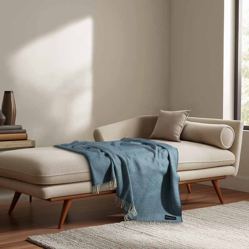 Beige sofa with a blue blanket in a room with large windows.