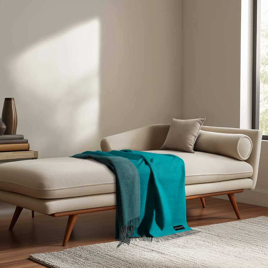 Beige chaise lounge with a teal blanket in a modern living room.