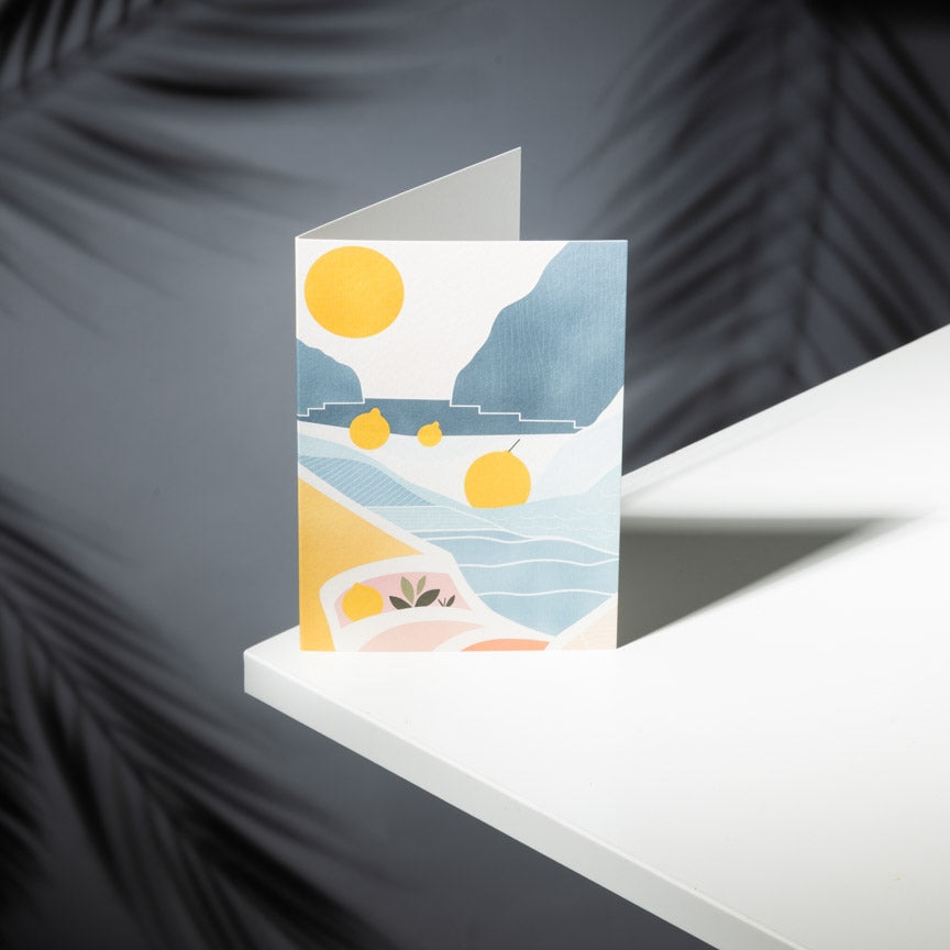 Greeting card with beach scene design on a white surface with dark background