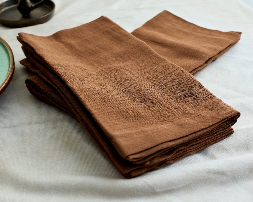 Folded brown cotton napkins on a white surface