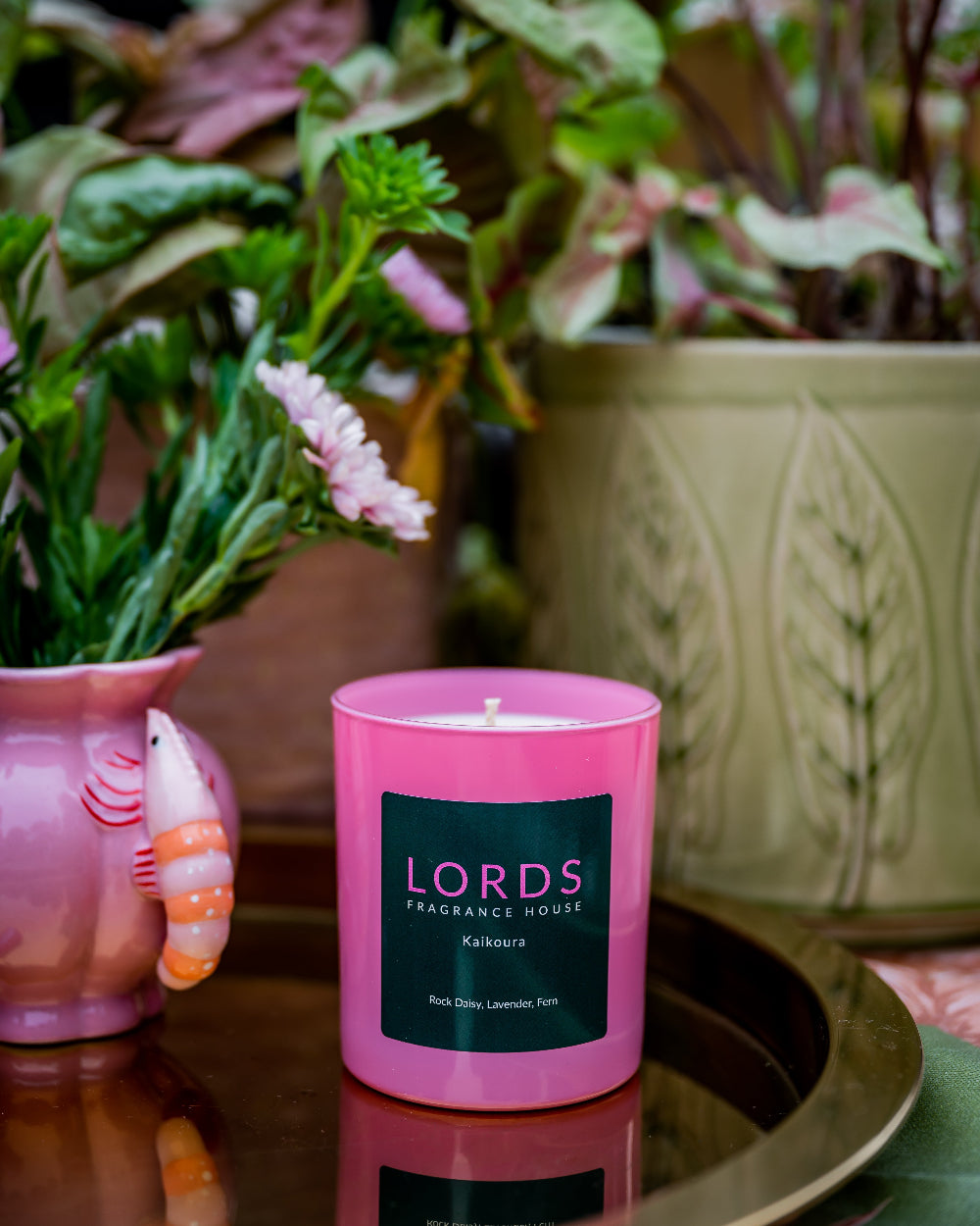 Pink candle with a label in front of potted plants