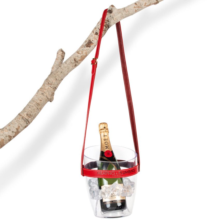 Champagne bottle in a clear holder with red handle against a white background