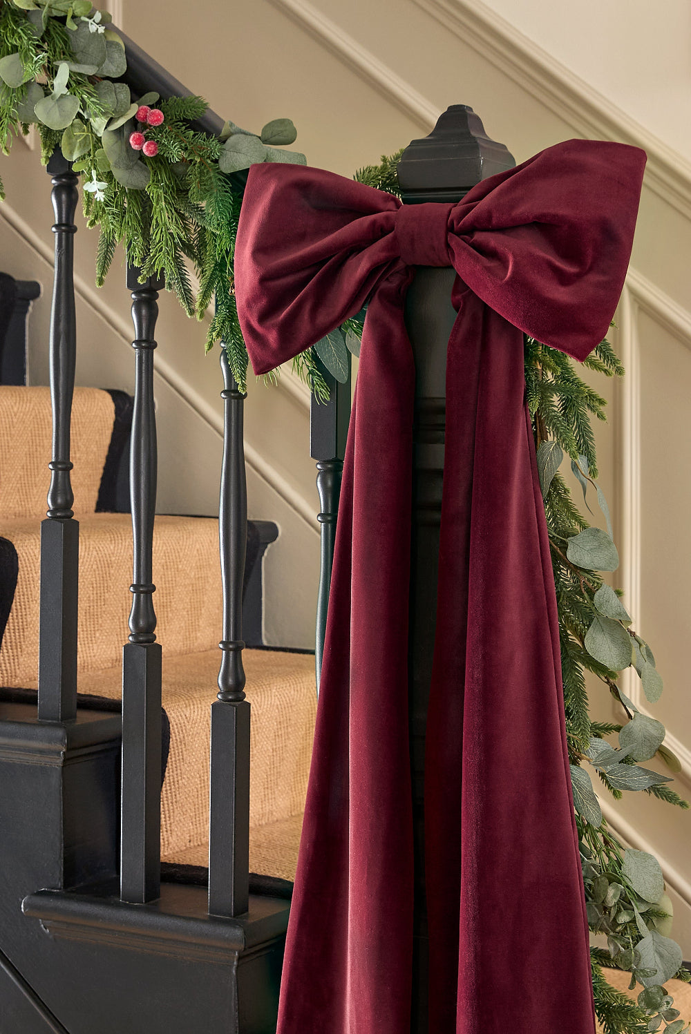 Kika Bespoke oversized burgundy velvet Christmas bow styled on a staircase