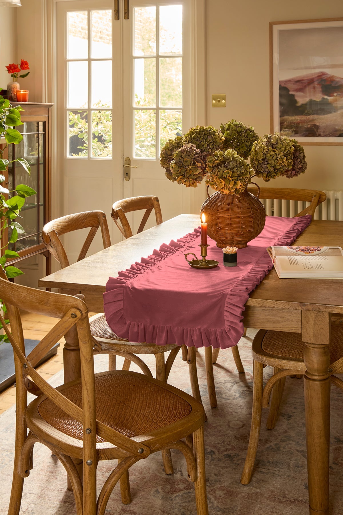 Dining room with wooden table and chairs, kika bespoke dusty pink table runner, and decorative elements.