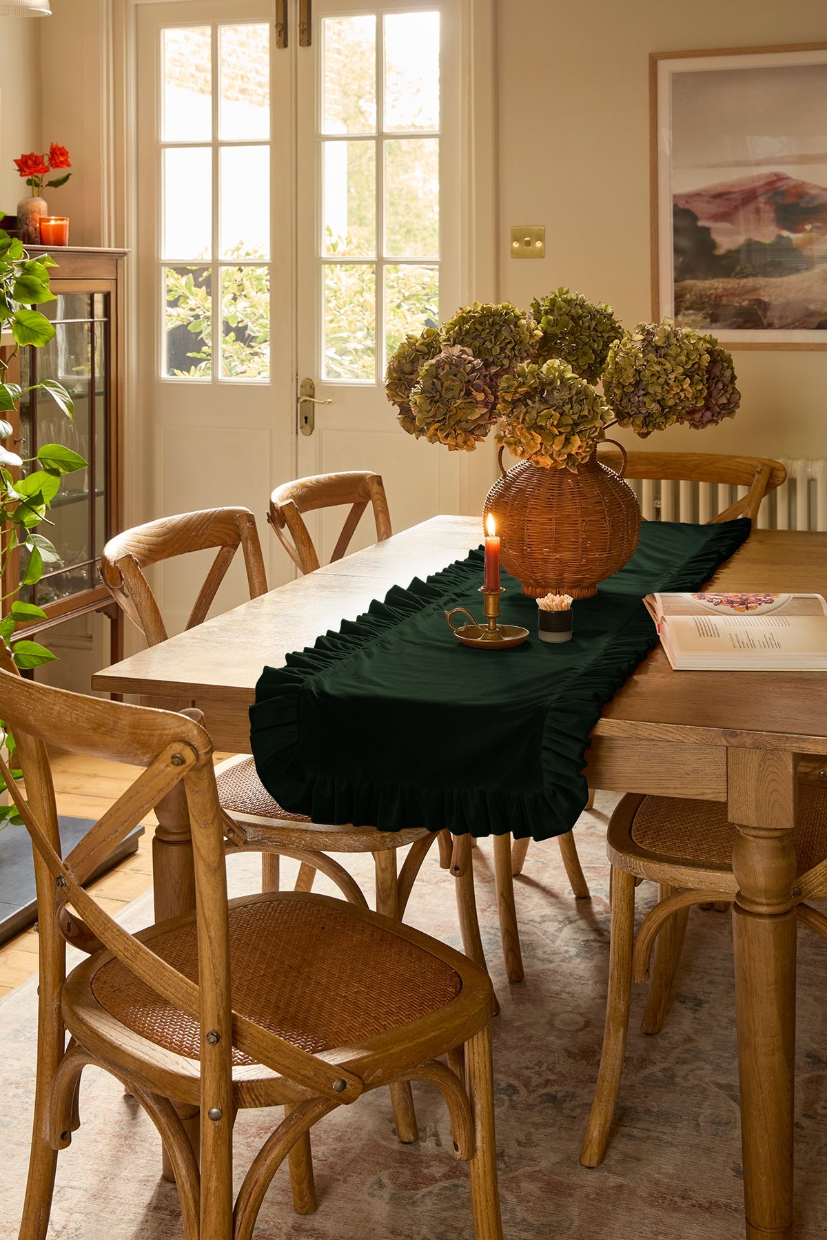 Dining room with wooden table and chairs, kika bespoke forest green runner, and decorative items.