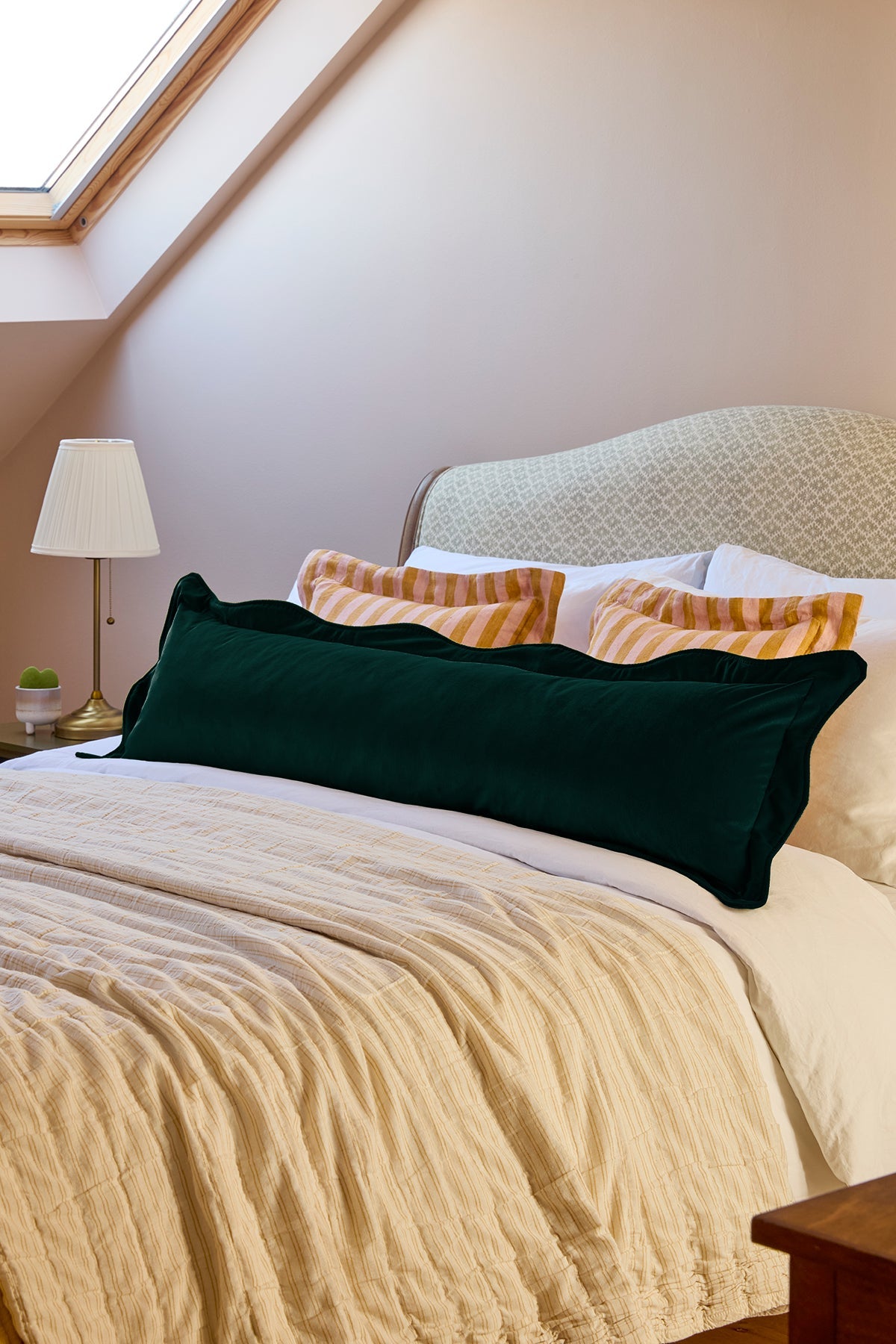 Bedroom with a bed featuring green and yellow pillows and a lamp on a nightstand.