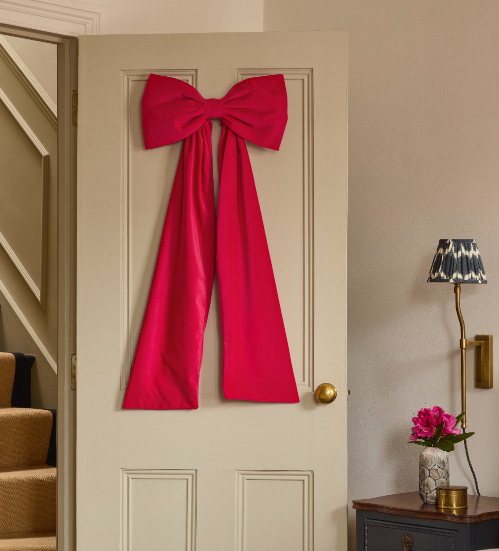 Kika Bespoke hot pink velvet bow displayed on an indoor door