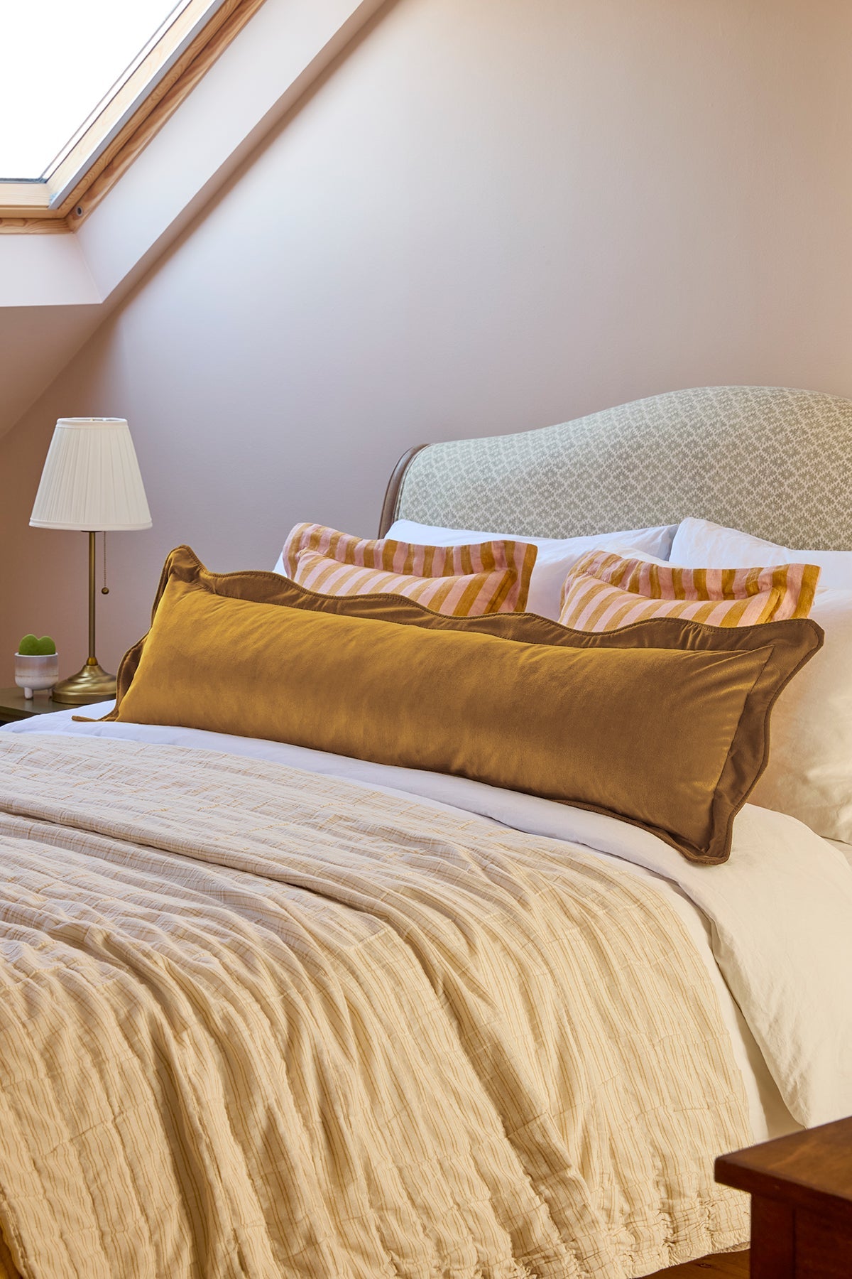 Bedroom with a bed featuring patterned headboard and colorful pillows.