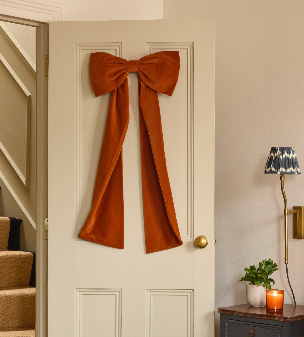 Kika Bespoke oversized rust velvet Christmas bow displayed on an indoor door