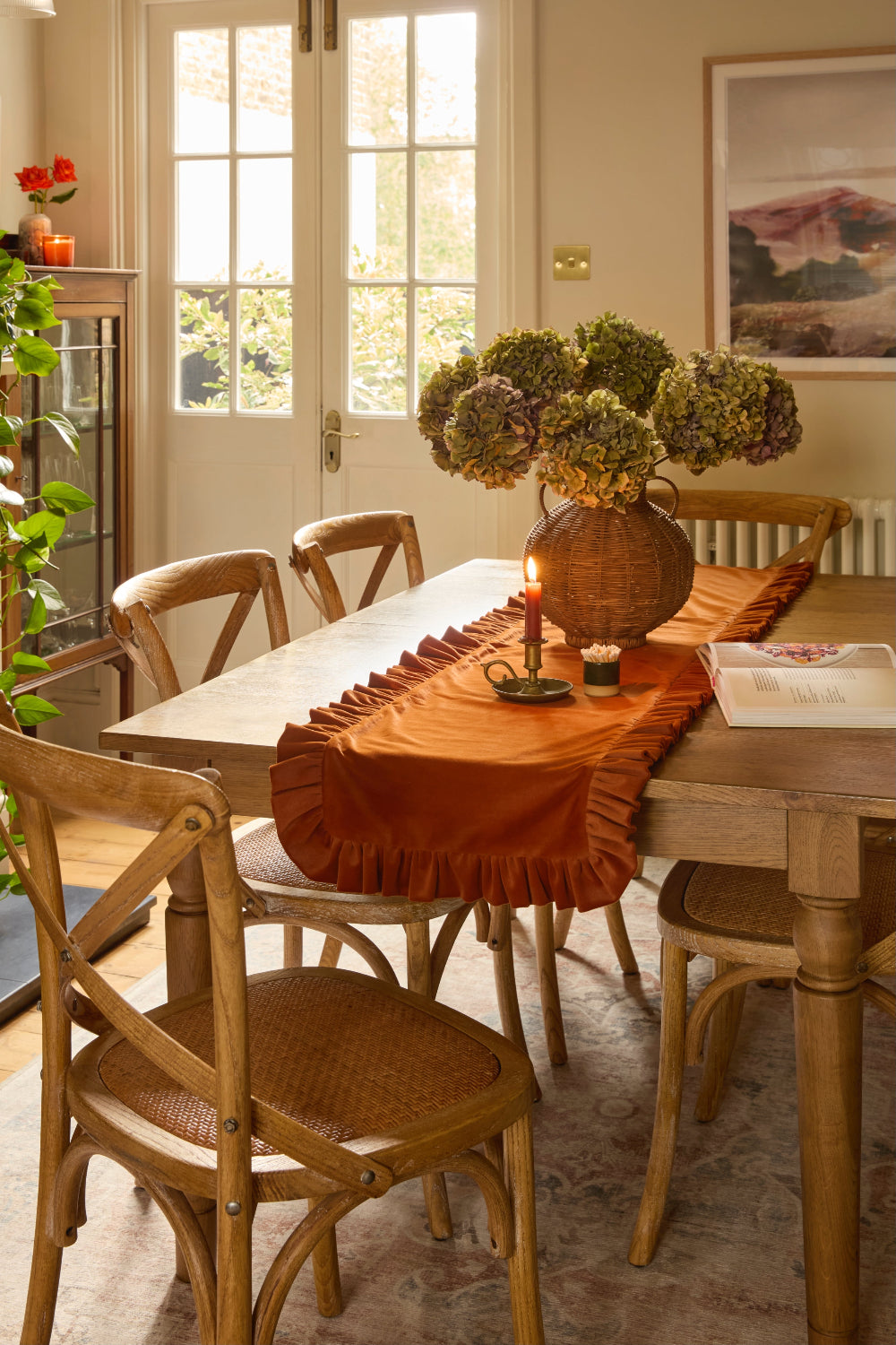 Dining room with wooden table and chairs, orange runner, and decorative elements.