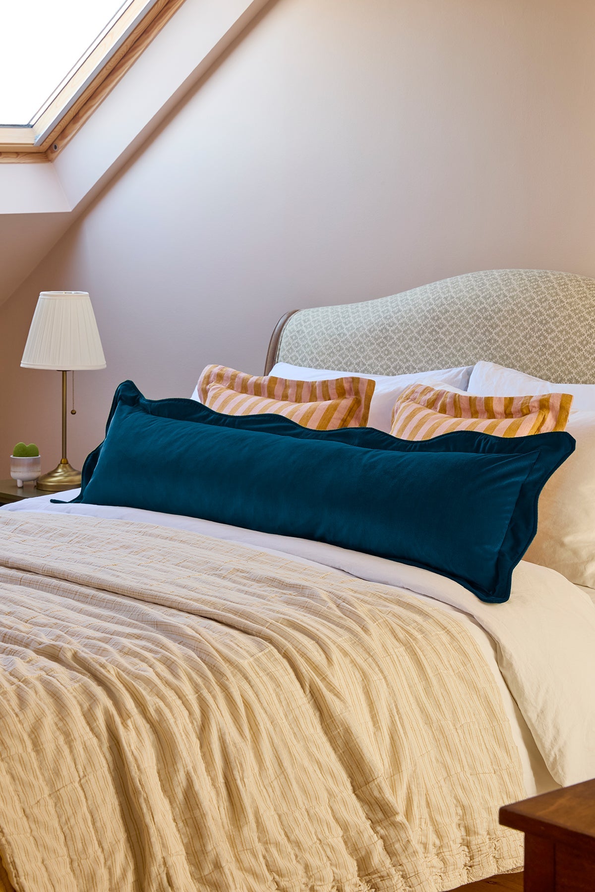 Bedroom with a bed featuring colorful pillows and a lamp on a nightstand.