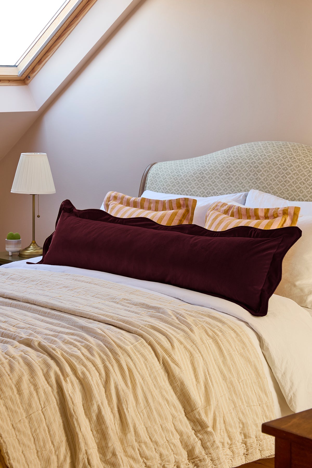 Bedroom with a bed featuring patterned headboard and colorful pillows.
