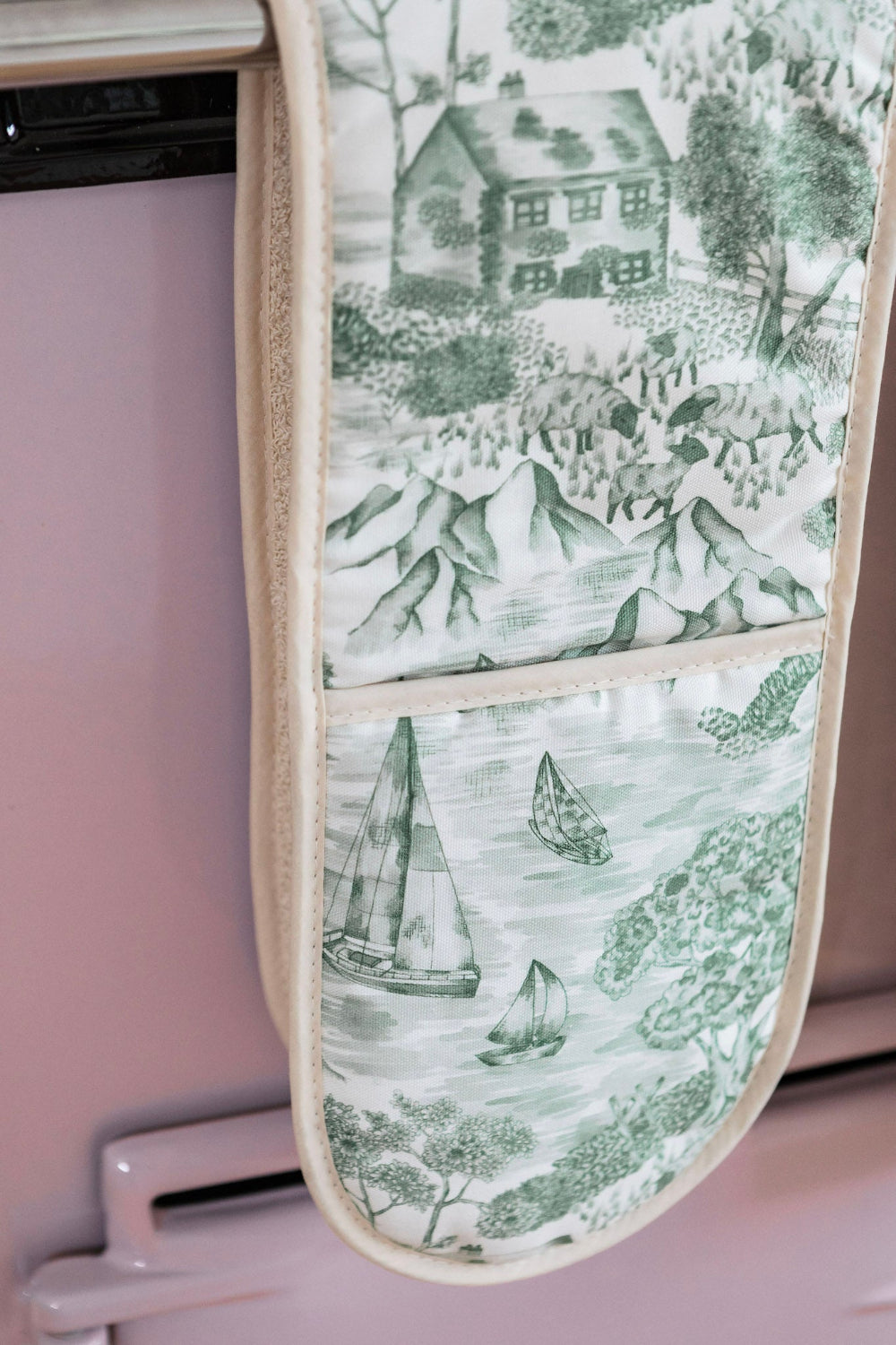 Oven mitt with Lake District scenic design hanging on a pink appliance