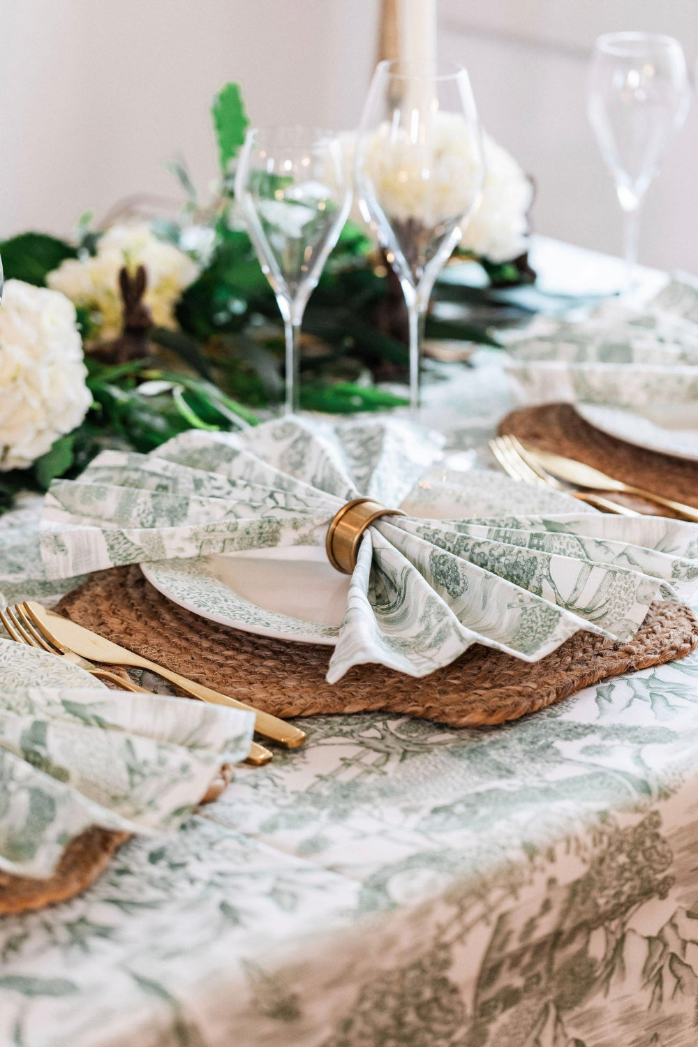Elegant table setting with floral centerpieces, glassware, and patterned napkins.