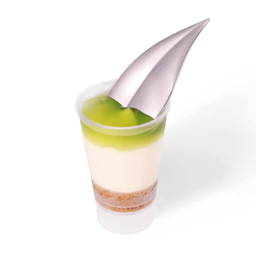 Dessert shot with green and white layers and a silver leaf spoon on a white background