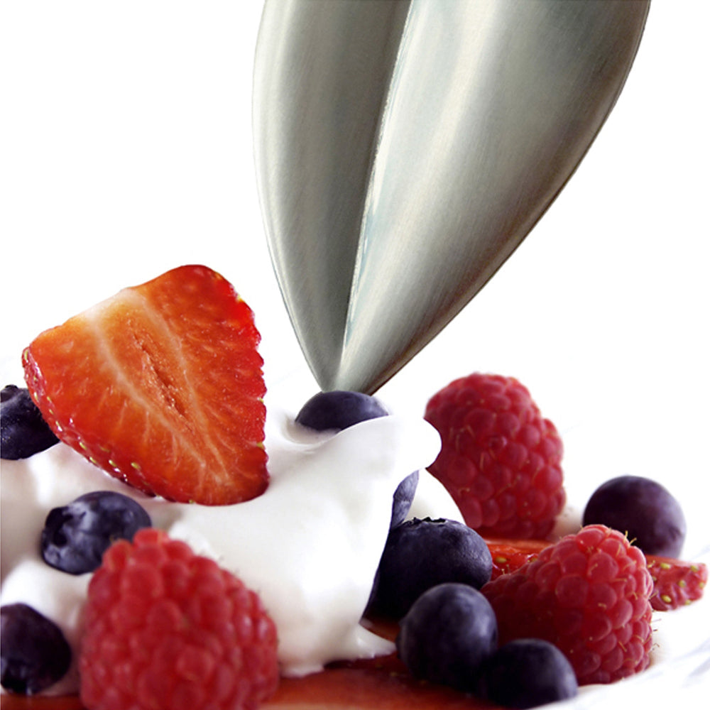 Spoon dipping into a dessert with whipped cream and berries on a white background