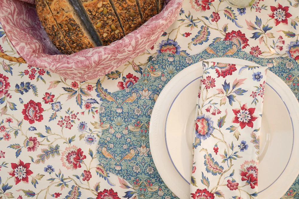 Decorative table setting with floral tablecloth, plates, and napkin.