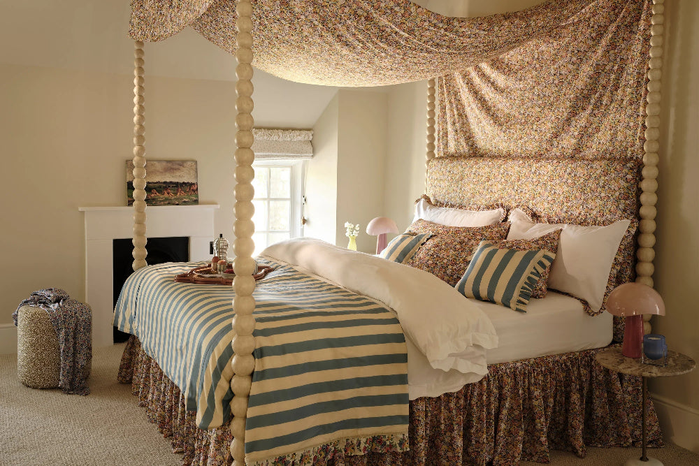 Decorative bedroom with canopy bed, striped bedding, and floral curtains.