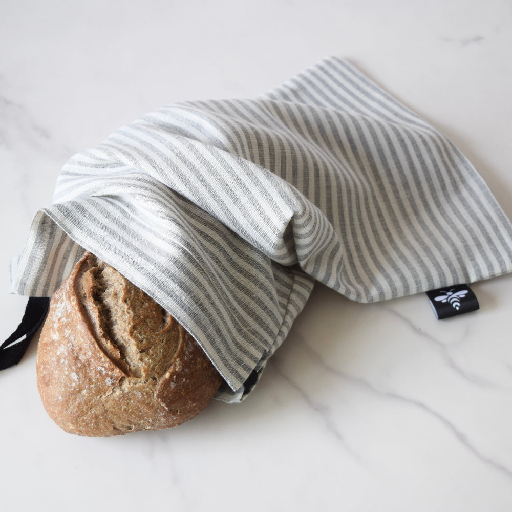 Loaf of bread wrapped in a striped drawstring bag on a white surface