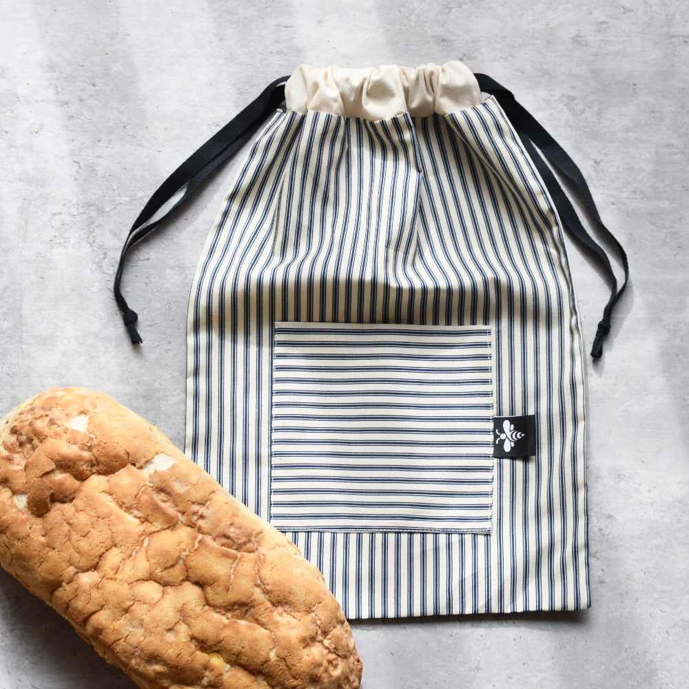Striped drawstring bag with a loaf of bread on a grey surface