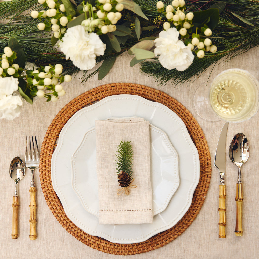 Elegant table setting with white plates, woven placemat, and decorative elements.